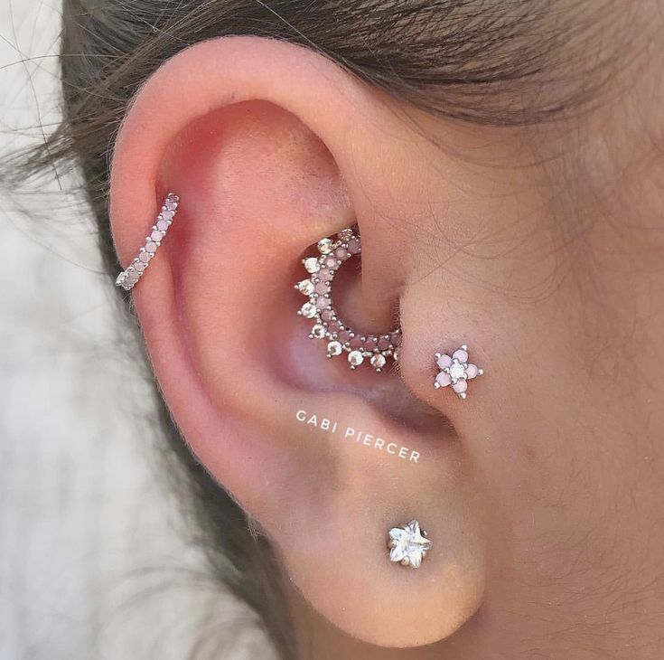 an ear with three different piercings on top of it and the bottom one has two stars