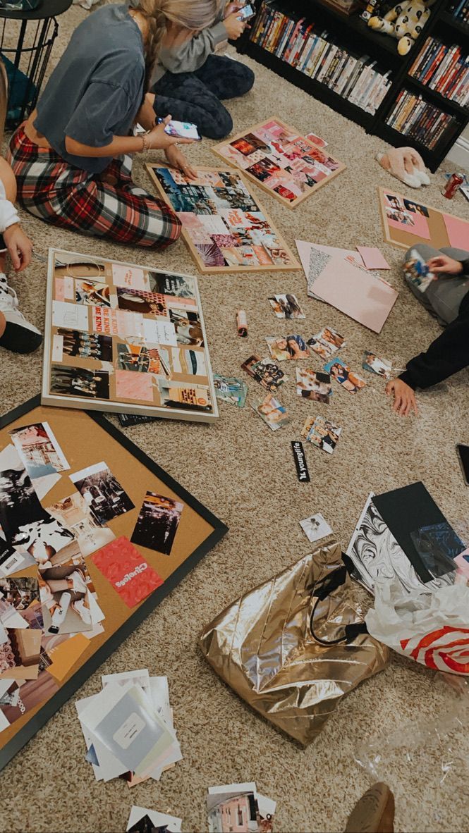 several people sitting on the floor looking at pictures and papers that have been cut up