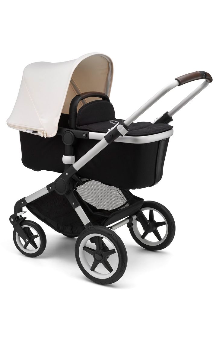 a baby stroller with a white and black cover on the top, in front of a