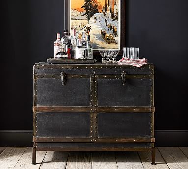 an old trunk is filled with liquor bottles and glasses on the table next to it