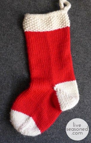 a red and white knitted christmas stocking hanging from a hook on the floor