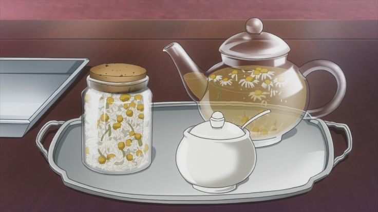 a glass teapot with flowers on it sitting next to a jar filled with liquid