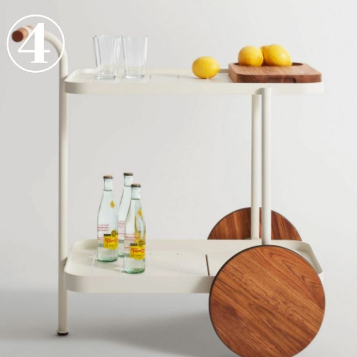 a white cart with drinks and lemons sitting on top of it next to a cutting board