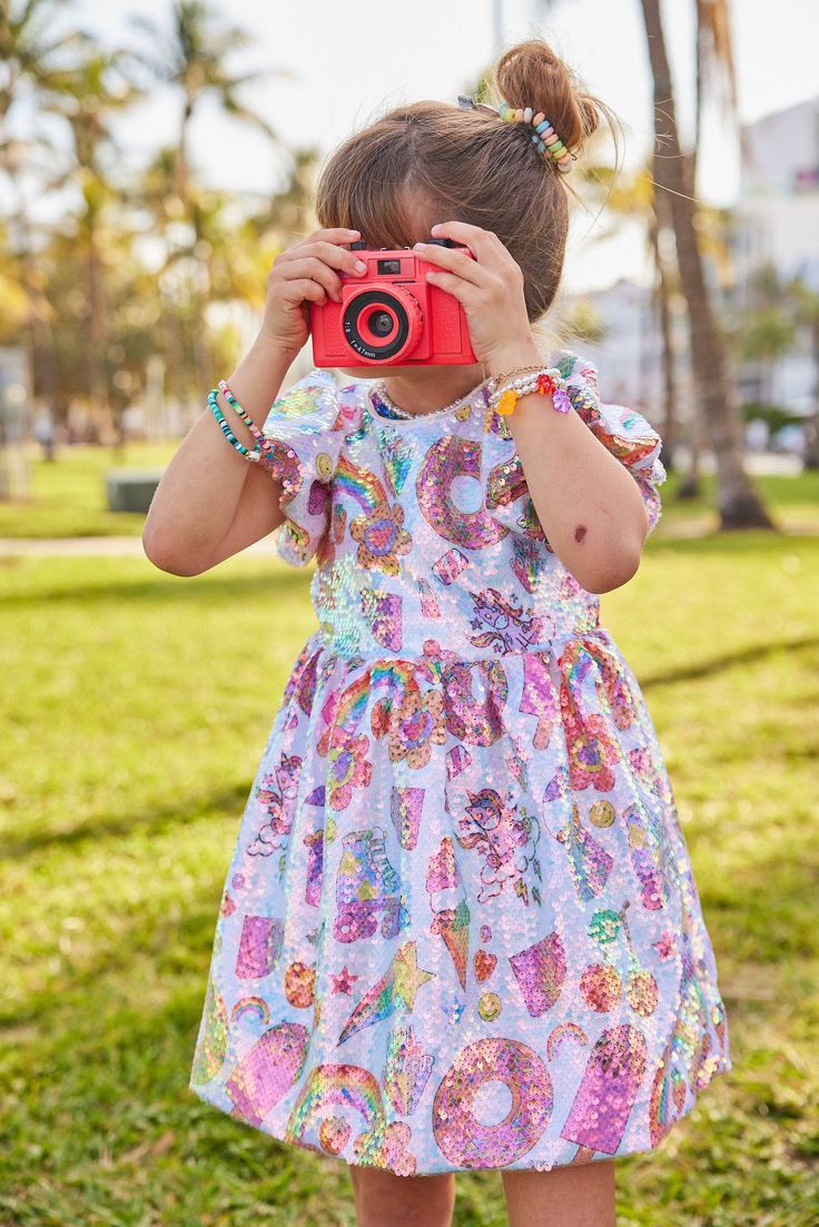 Description: Playful and colorful sequin dress adorned with fun summer-themed prints. Features puffy short sleeves and a flared skirt for a cute and girly silhouette. The all-over sequin detailing adds sparkle and shine, making it perfect for any festive occasion. Material & Care: Fabric: High-quality polyester with sequin embellishments. Care Instructions: Hand wash cold. Lay flat to dry. Do not bleach. Avoid ironing directly on the sequins. Handle with care to preserve the sequin detailing. Festive Summer Dress With Short Sleeves, Summer Festive Short Sleeve Sequin Dress, Spring Festive Short Sleeve Sequin Dress, Spring Festive Sequin Dress With Short Sleeves, Summer Festive Glitter Dresses, Playful Sequin Party Dresses, Playful Sequined Party Dress, Playful Party Dress With Sequins, Pink Short Sleeve Sequin Dress For Summer