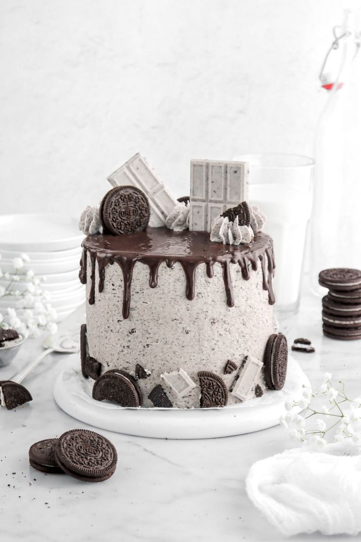 an oreo cookie cake with chocolate icing and cookies on the table next to it