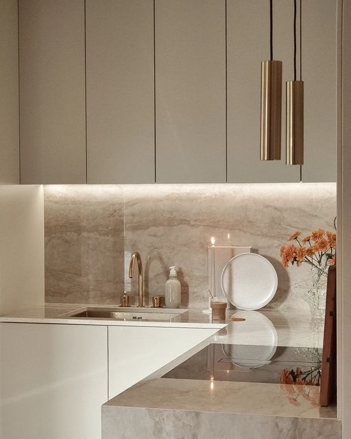 a kitchen with marble counter tops and white cupboards next to a vase filled with flowers