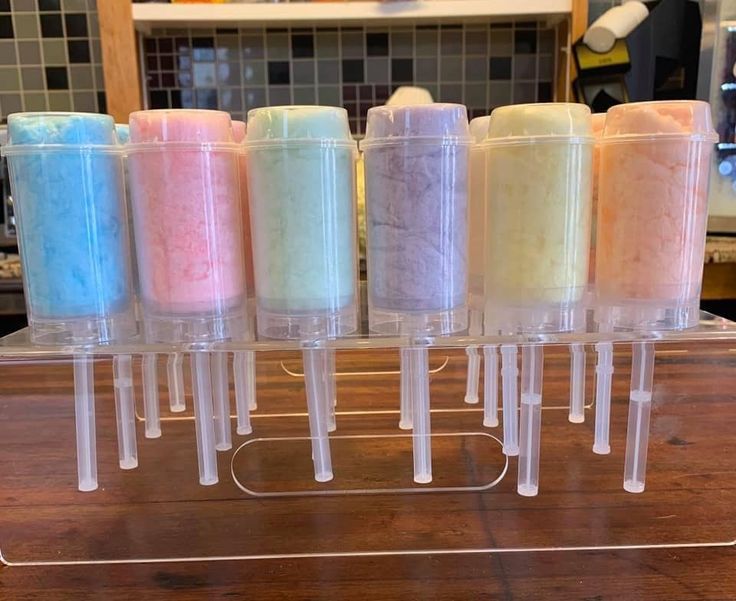 five different colored candles in plastic containers on a counter