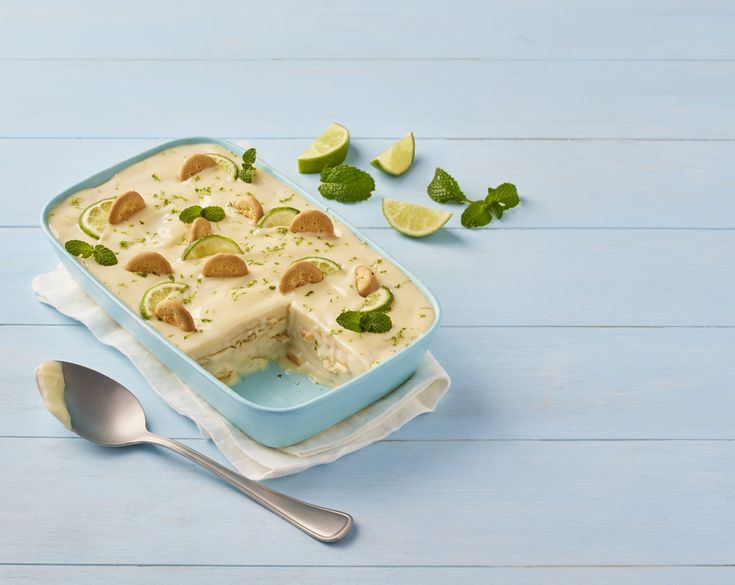 a blue dish filled with food next to a spoon and some mint leaves on the table