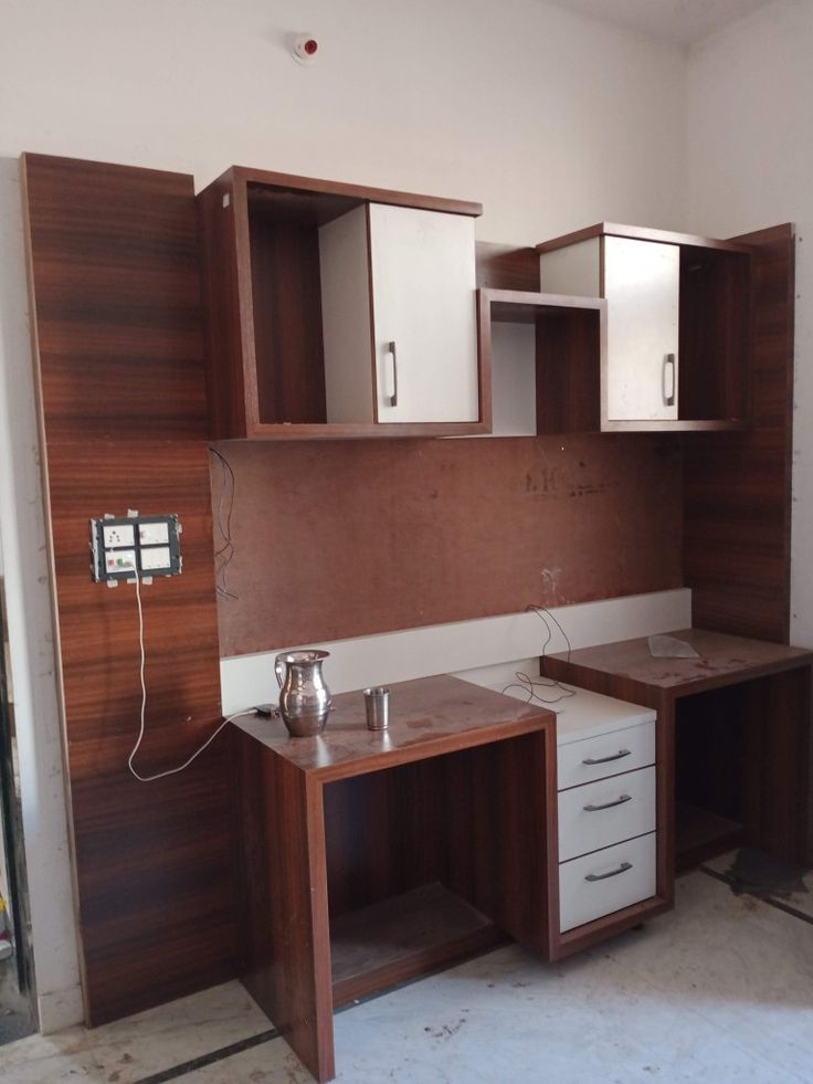 an empty room with wooden cabinets and white cupboards on the wall next to it