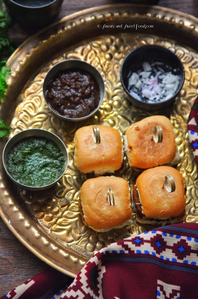 several small sandwiches on a gold plate with dipping sauces and green chutney