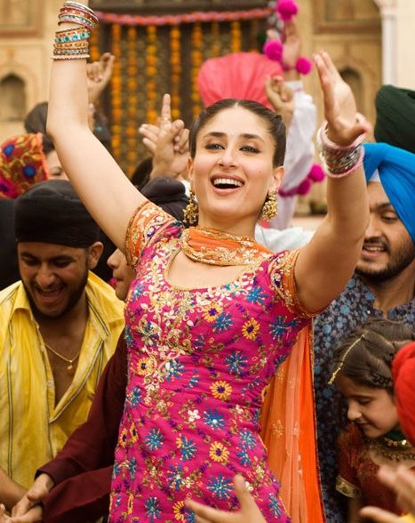 a woman in a colorful dress dancing with other people around her and smiling at the camera