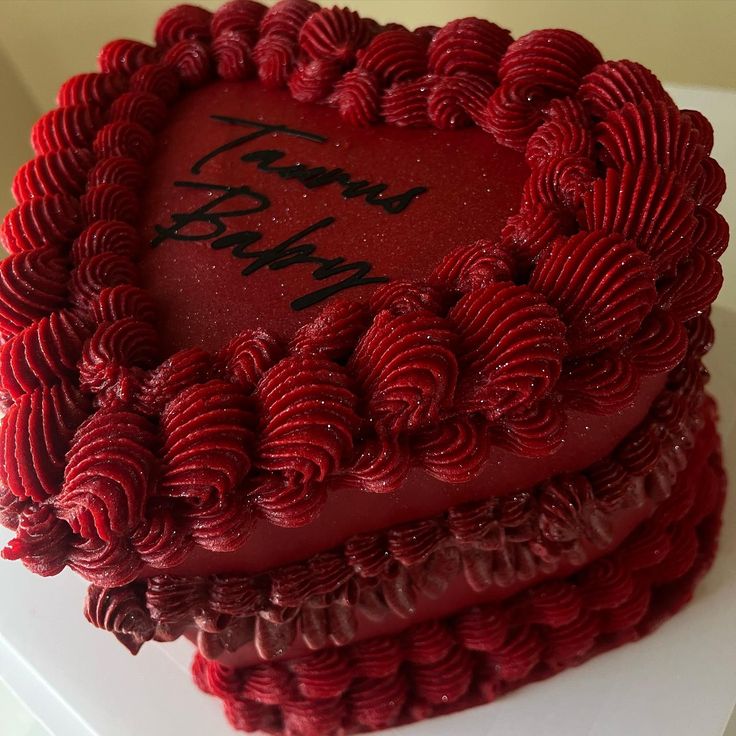 a red heart shaped cake with writing on it