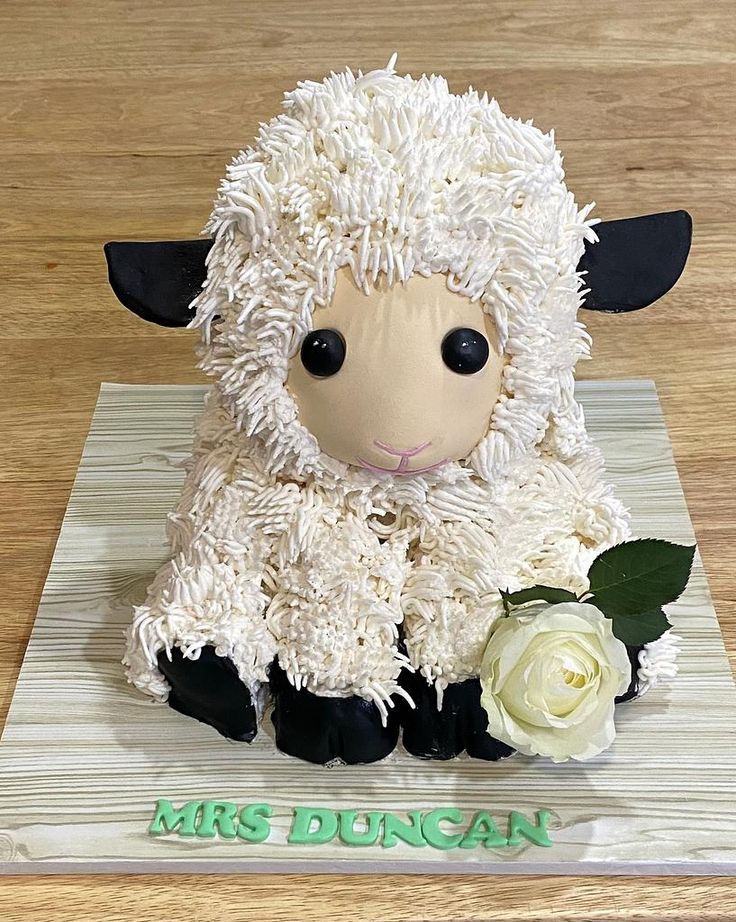 a cake made to look like a sheep sitting on top of a wooden table with white flowers