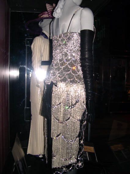 a mannequin dressed in silver sequins and black leather gloves is on display