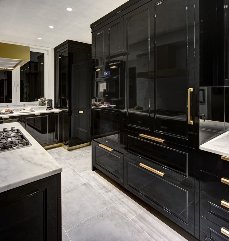 a large kitchen with black cabinets and marble counter tops