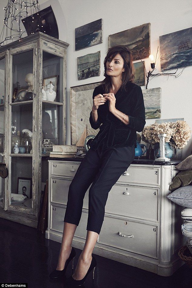 a woman sitting on top of a dresser next to a white cabinet and chandelier