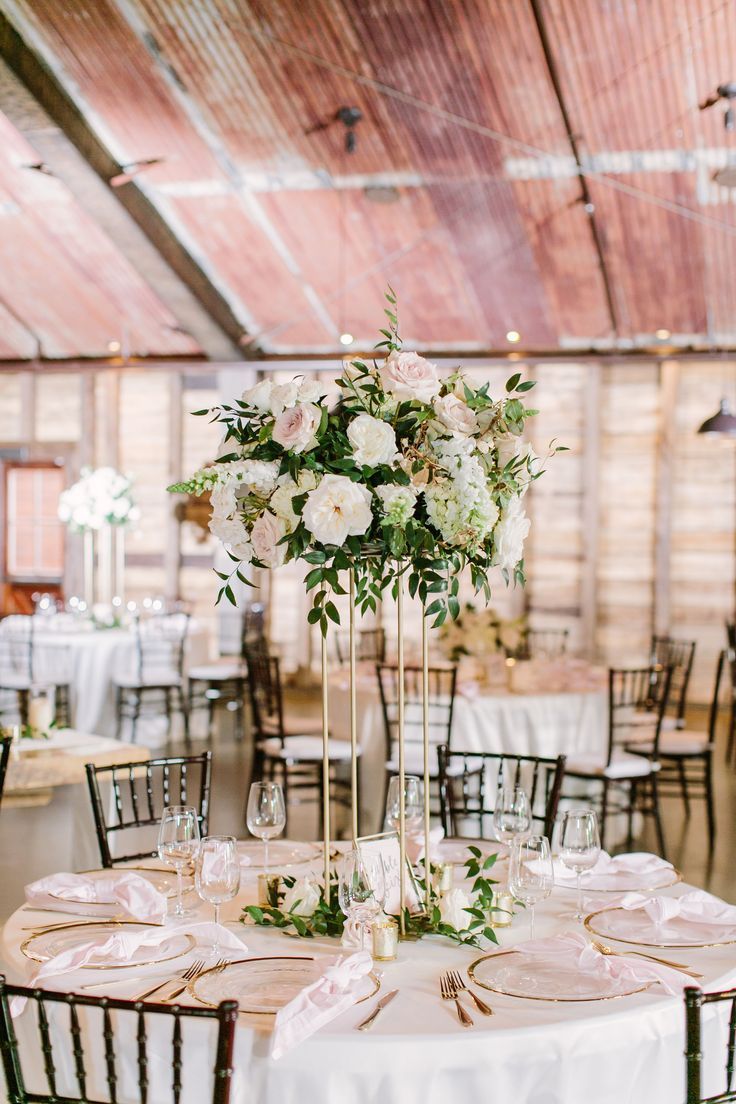 a tall vase filled with white flowers sitting on top of a table covered in pink napkins