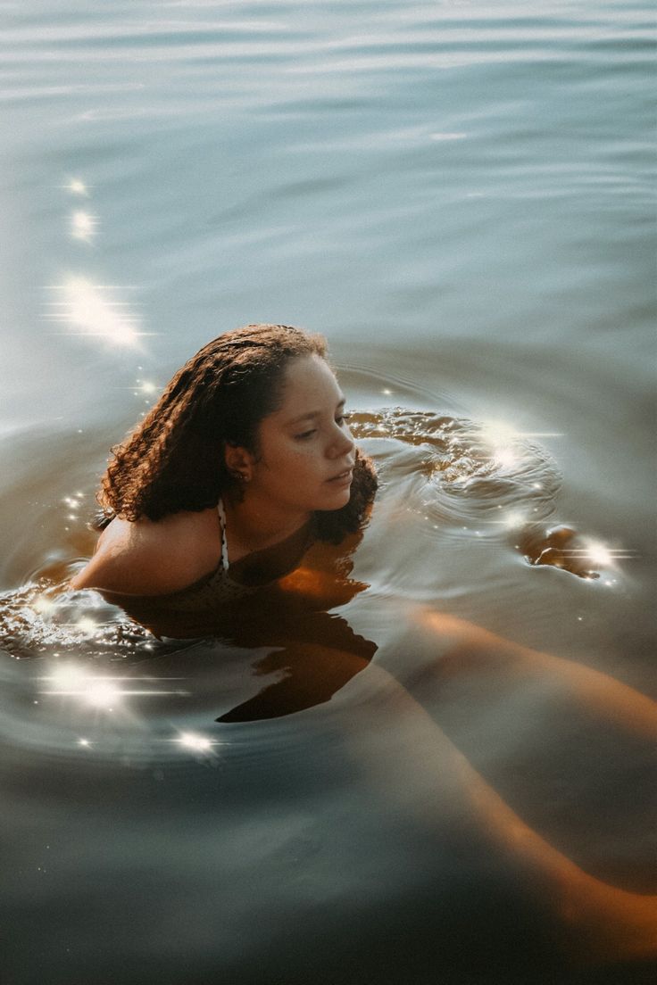 a woman is floating in the water with her hair blowing back