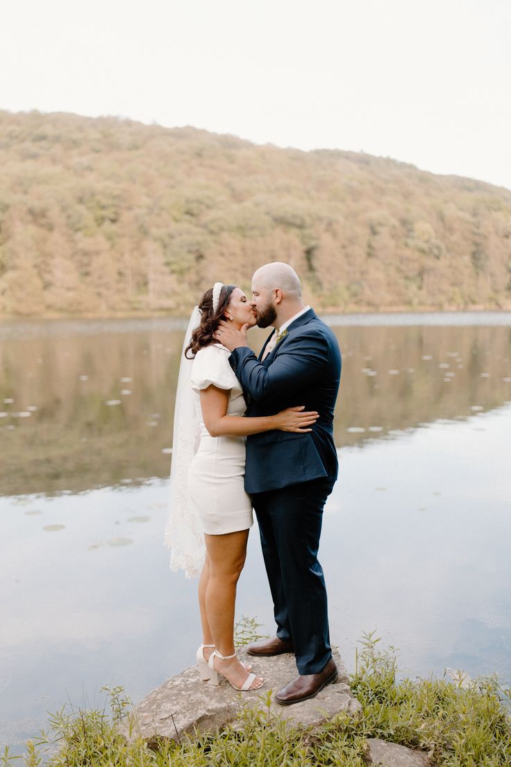 a bride and groom kissing by the water