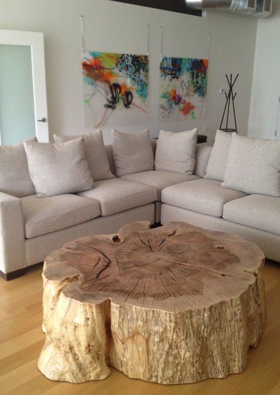 a living room filled with furniture and a large tree stump table in front of the couch