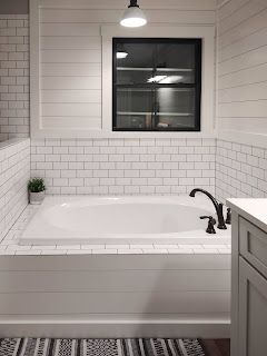 a bathroom with a white tub and black accents on the walls, along with a striped rug