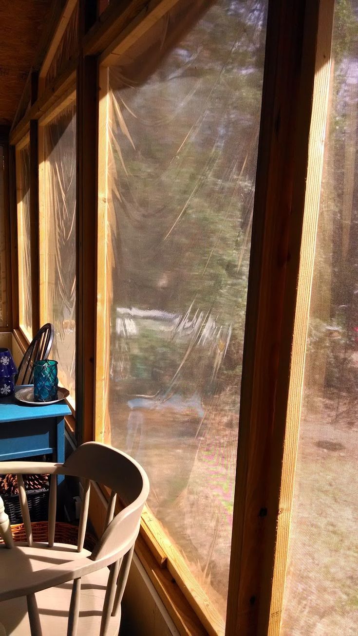 there is a table and chairs on the porch by the window in this house with lots of windows