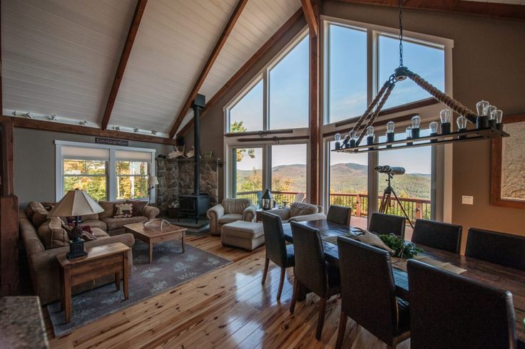 a large open living and dining room area with wood flooring, high vaulted ceilings, and stone fireplace