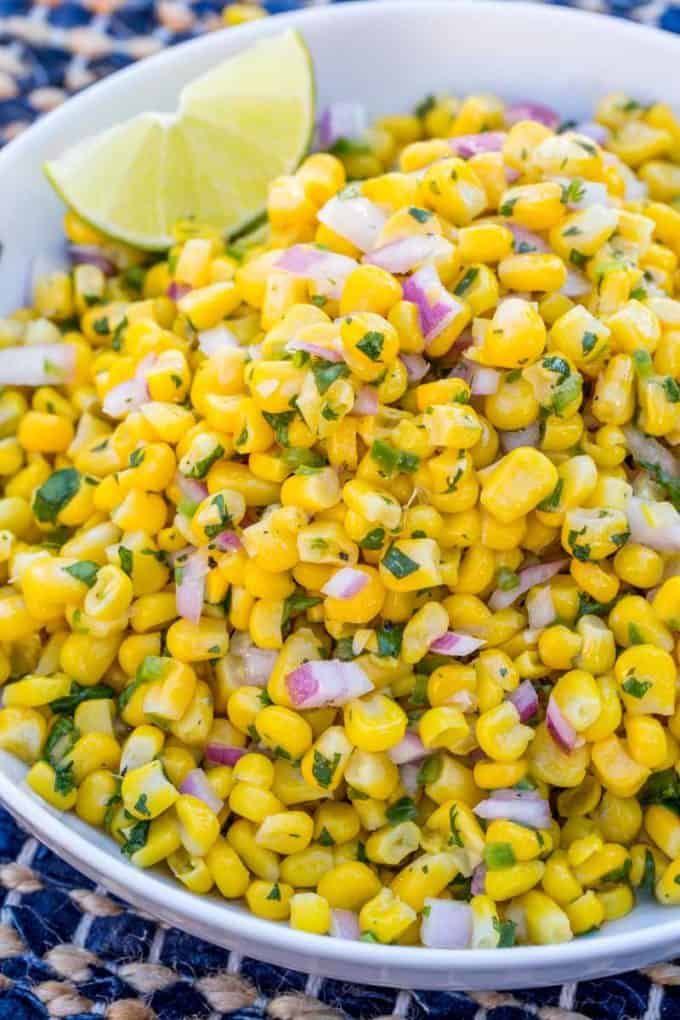 corn salad with cilantro and lime in a white bowl on a blue tablecloth