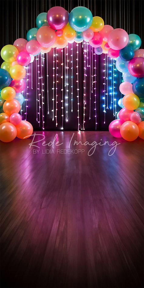 an arch made out of balloons and streamers on a wooden floor with lights in the background