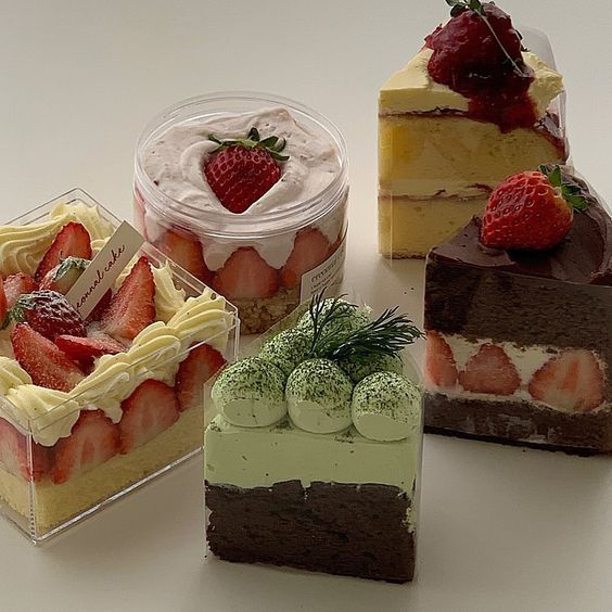 four different types of desserts in plastic containers on a white counter top with strawberries