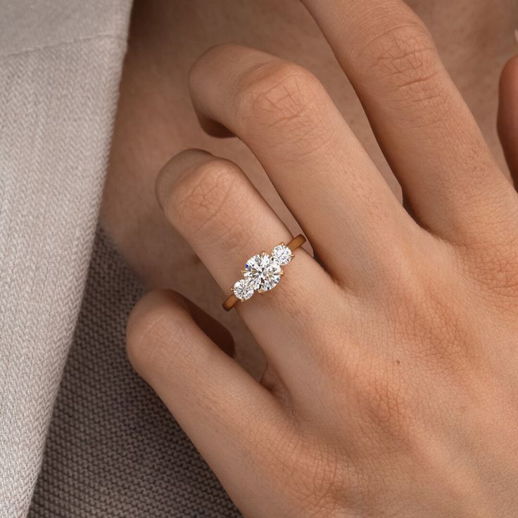 a woman's hand with a three stone diamond ring on her left and right hand