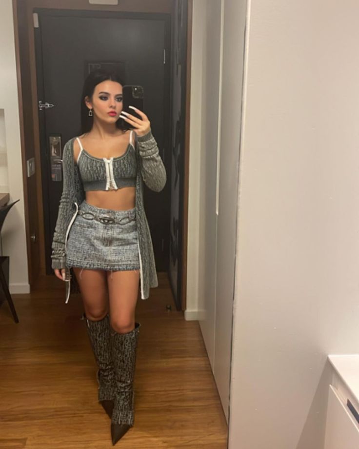 a woman is taking a selfie in the mirror while wearing boots and holding a cell phone