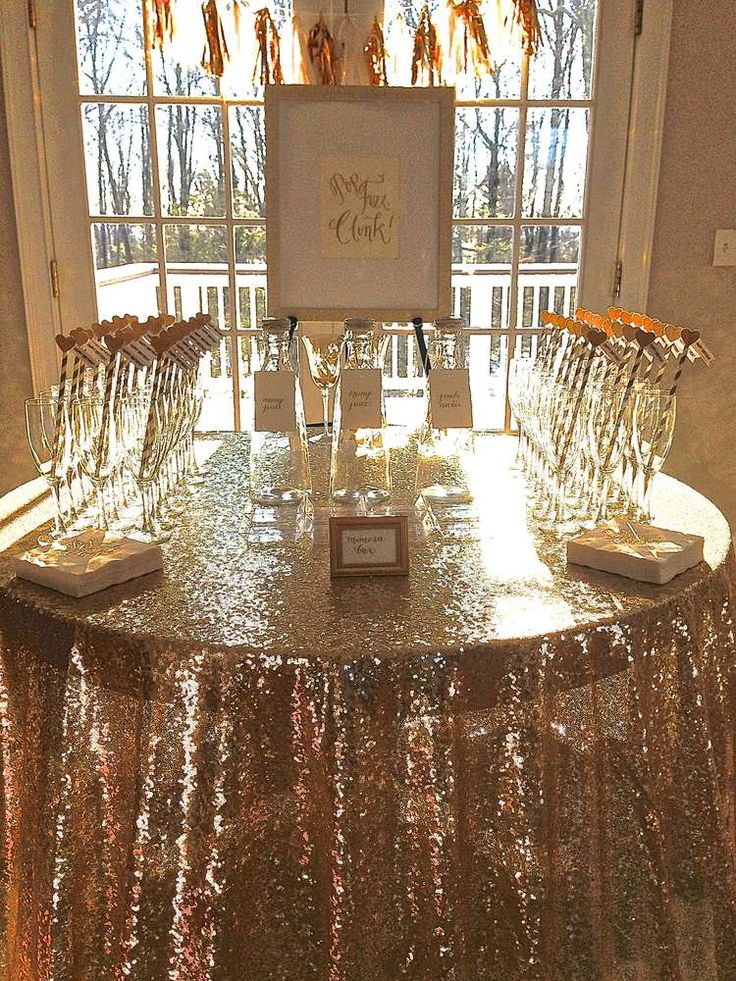 a table with wine glasses on it in front of a window and a sign that says sweet cider