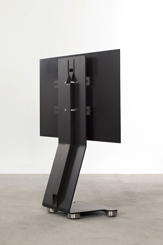 a black computer monitor sitting on top of a metal stand in front of a white wall