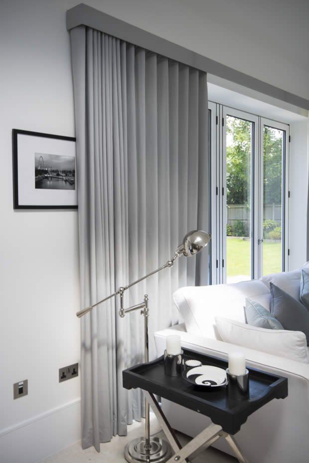 a living room with white furniture and curtains