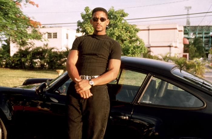 a man standing in front of a black car