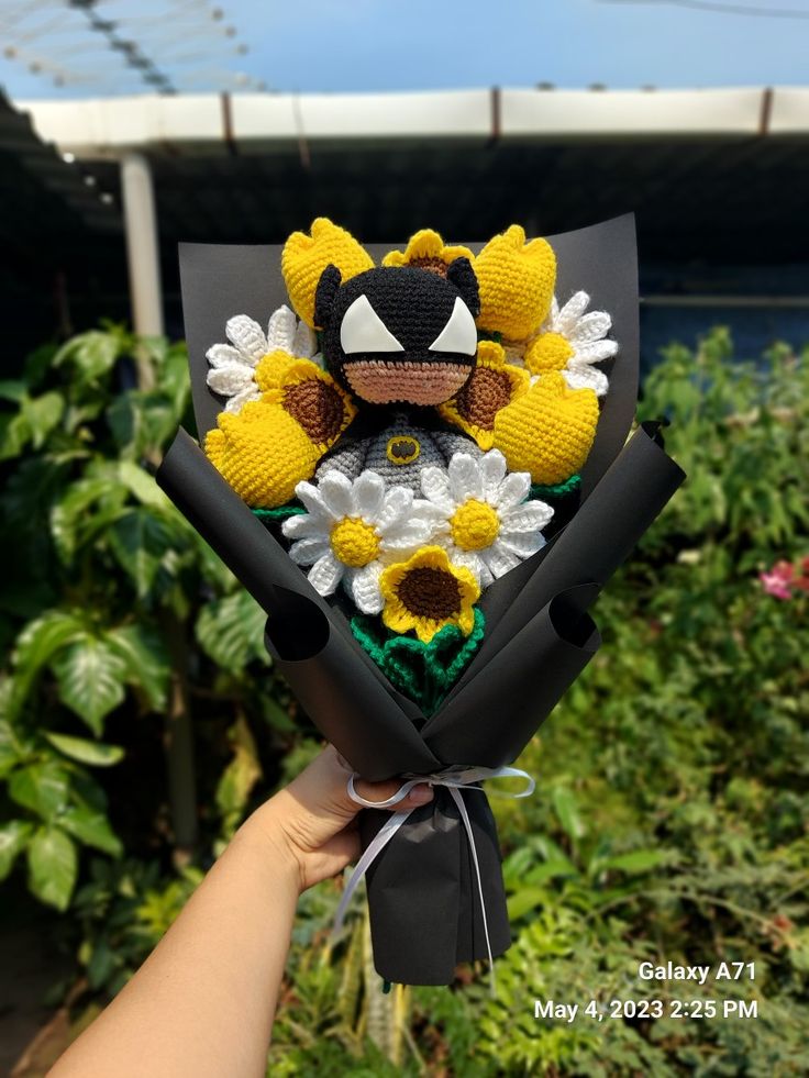 someone holding up a bouquet of flowers in front of some bushes and trees with the sunflowers on it