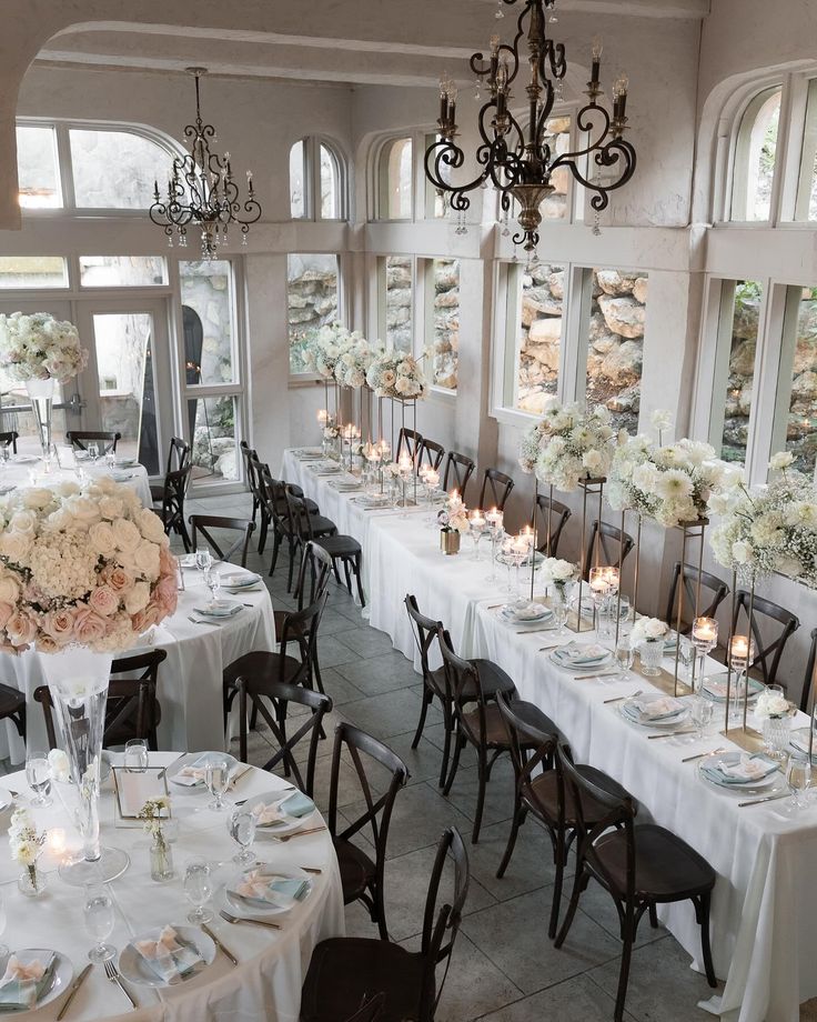 a room filled with lots of tables covered in white tablecloths and centerpieces