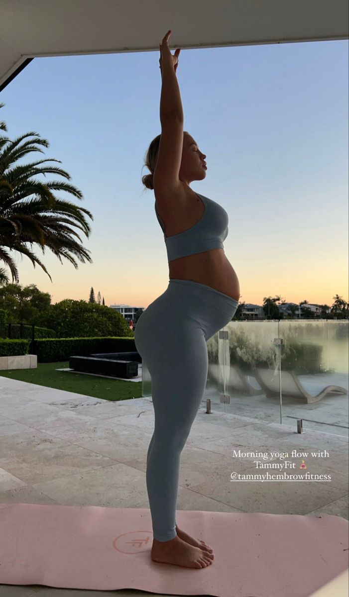 a pregnant woman is doing yoga outside in the sun light with palm trees behind her