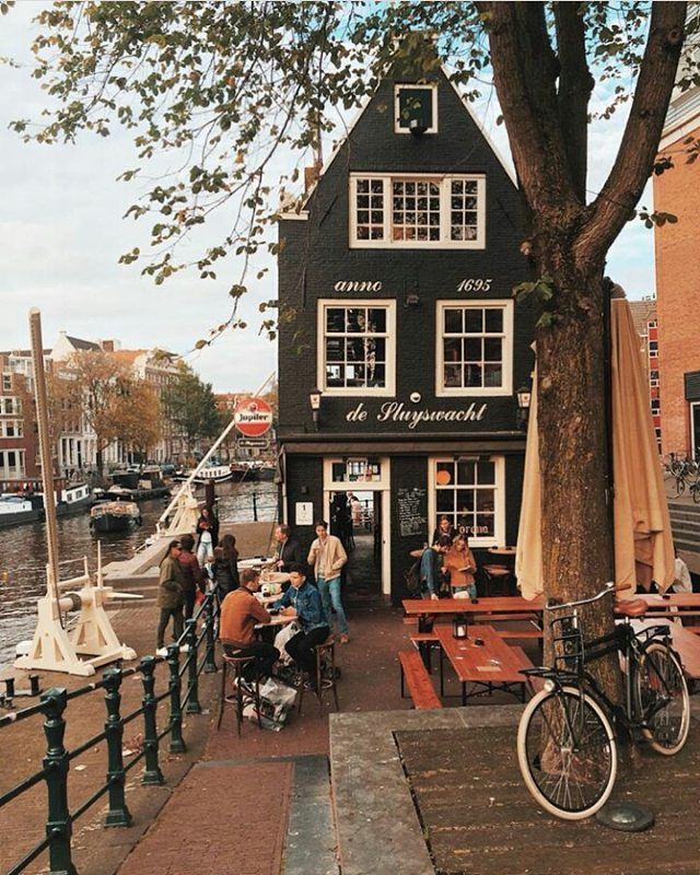 an instagram photo of people sitting at tables in front of a black and white house