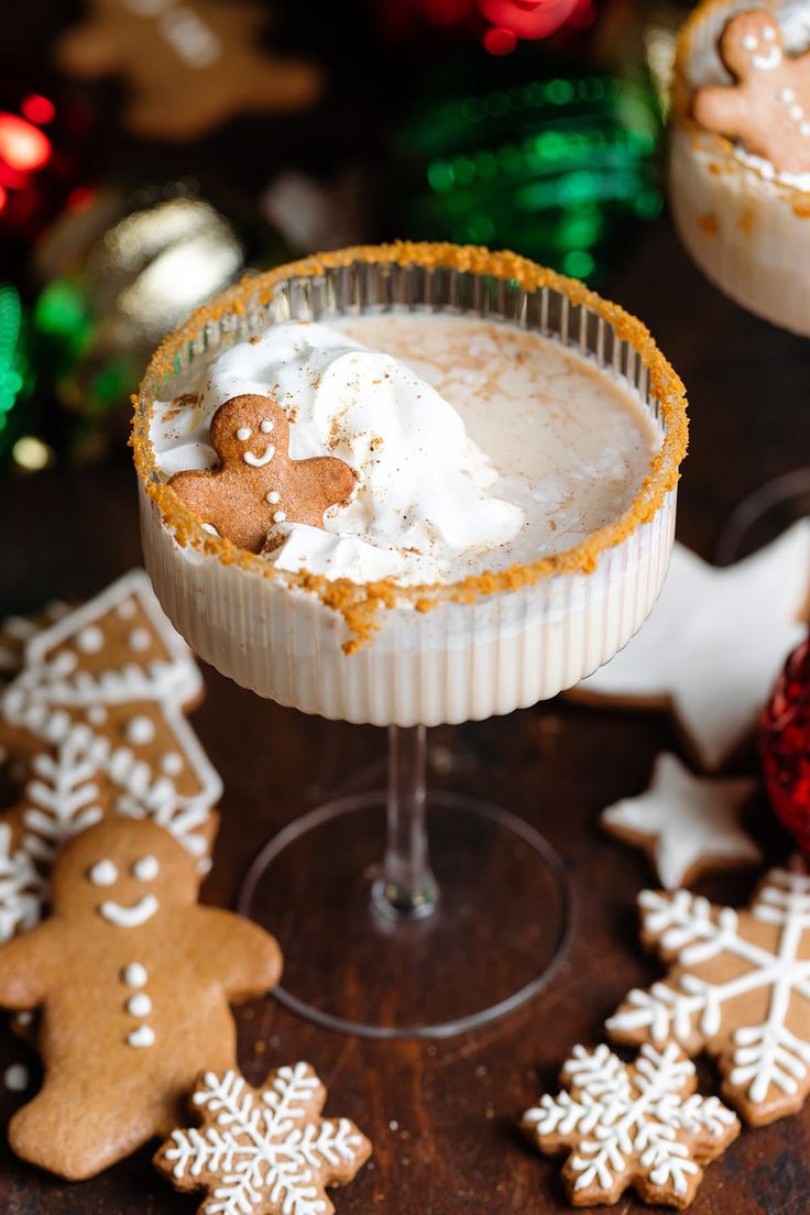 two desserts with gingerbread cookies and whipped cream in them on a wooden table