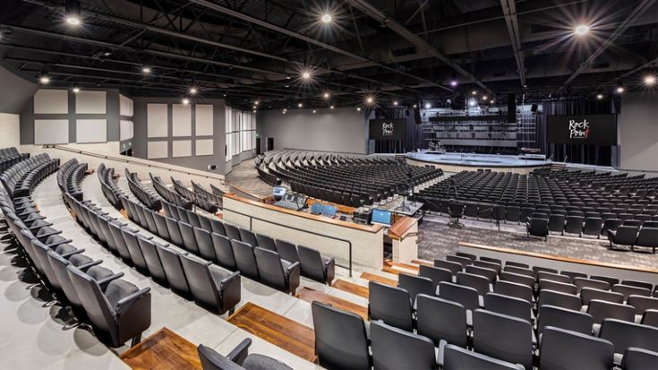 an empty auditorium filled with black chairs