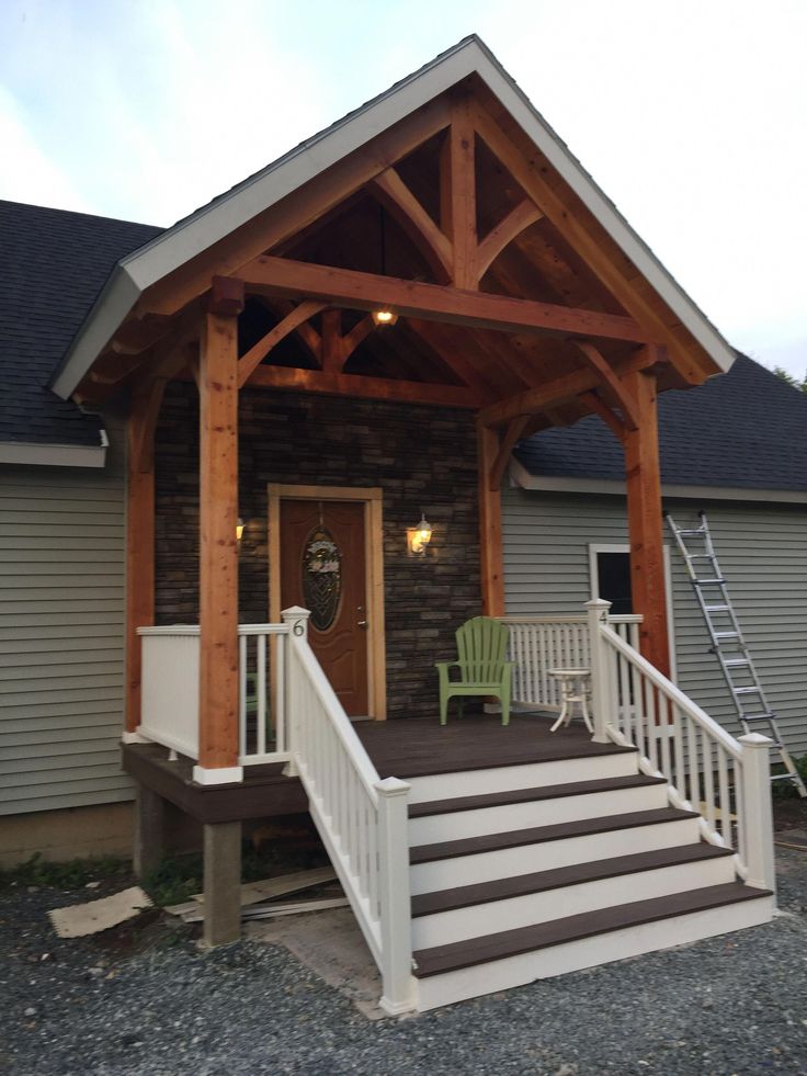 a porch with steps leading up to the front door and covered in wood planks