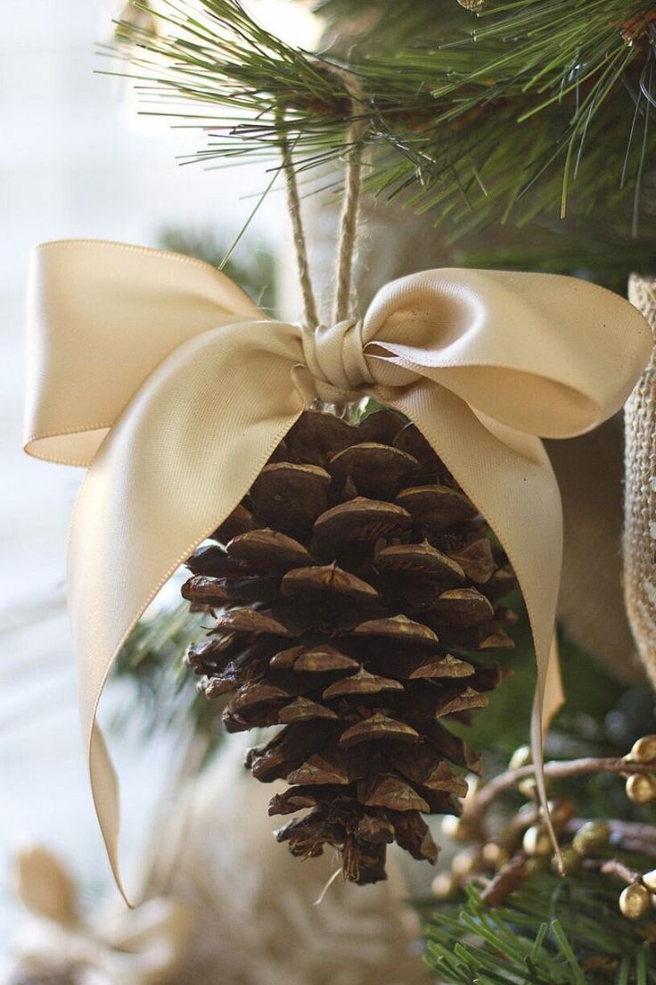 a pine cone ornament hanging from a christmas tree with a bow on it