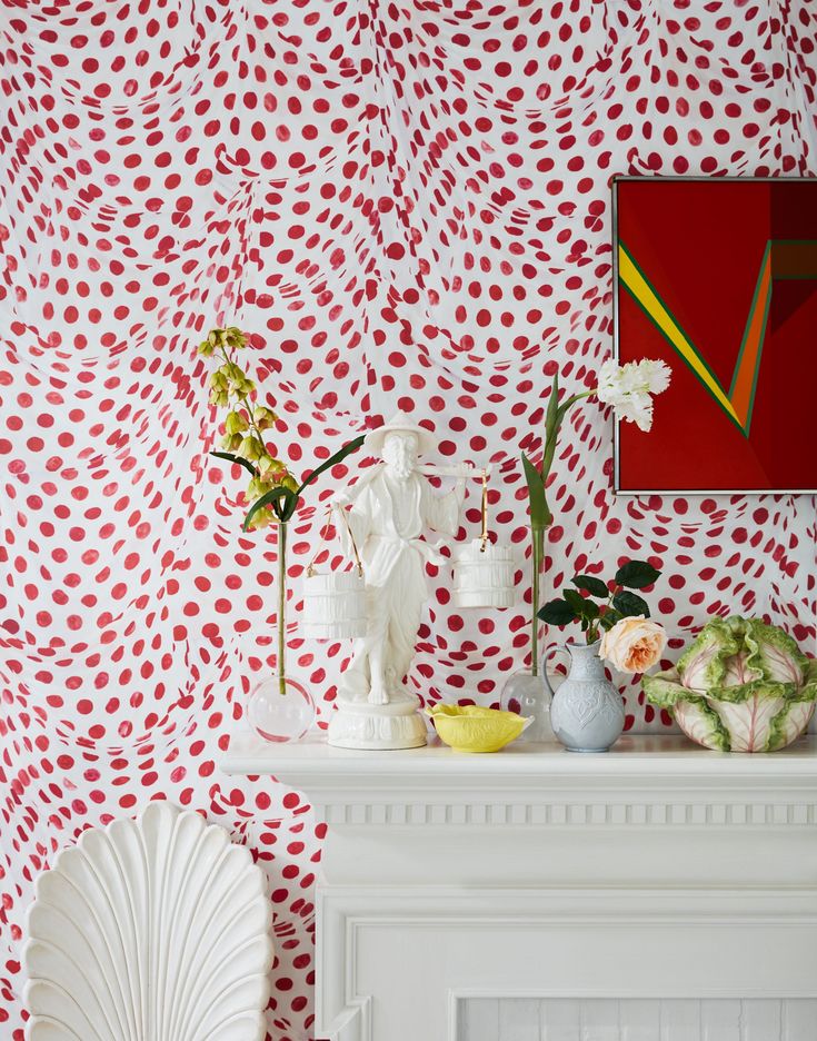 red and white wallpaper in a living room with flowers on the fireplace mantel