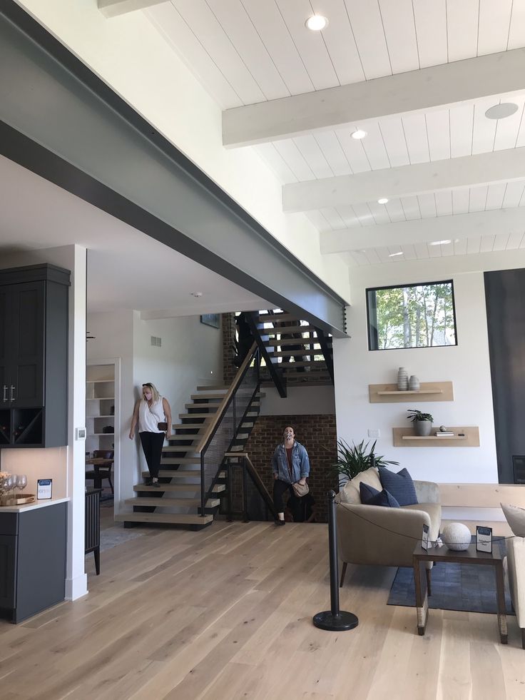 two men standing in the living room looking at something on the wall and stairs to the second floor