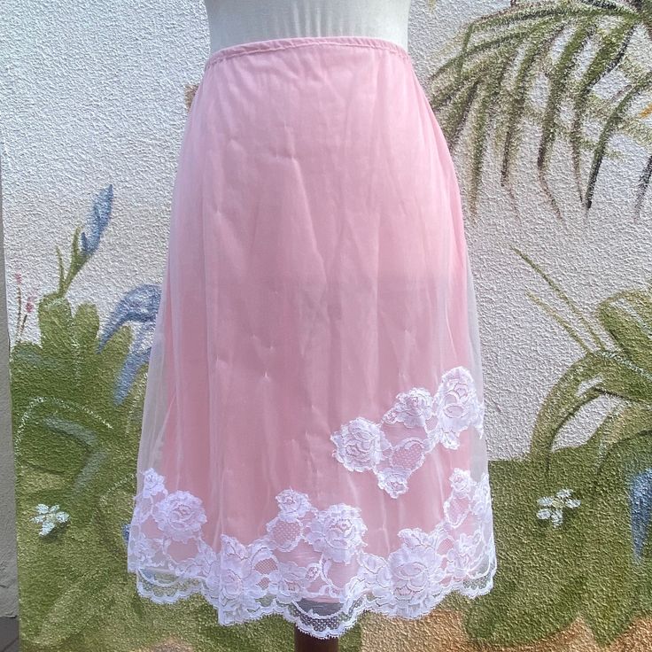 That feeling of confidence when wearing luxurious garments often begins with the ones that don't show! This is a beautiful pink slip that can be fashioned as an adorable skirt. It 2 layers, one pink and one a soft white overlay with floral lace. It's a beauty reminiscent of old Hollywood! Circa:  1960's Designer:  Unknown, no tag Size:  Small, Fits like Current Day Small. Please review measurements to ensure proper fit. Material:  100% Nylon Condition: In Good Vintage Condition Measurements: Wai Vintage Lace Trim Petticoat For Summer, Pink Lace Skirt For Spring, Elegant Pink Skirt With Lace Trim, Vintage Lace Petticoat For Summer, Pink Lined Skirt For Wedding, Spring Full Skirt Petticoat With Lace Trim, Spring Vintage Lace Petticoat, Feminine Lace Trim Skirt For Daywear, Feminine Daywear Skirt With Lace Trim