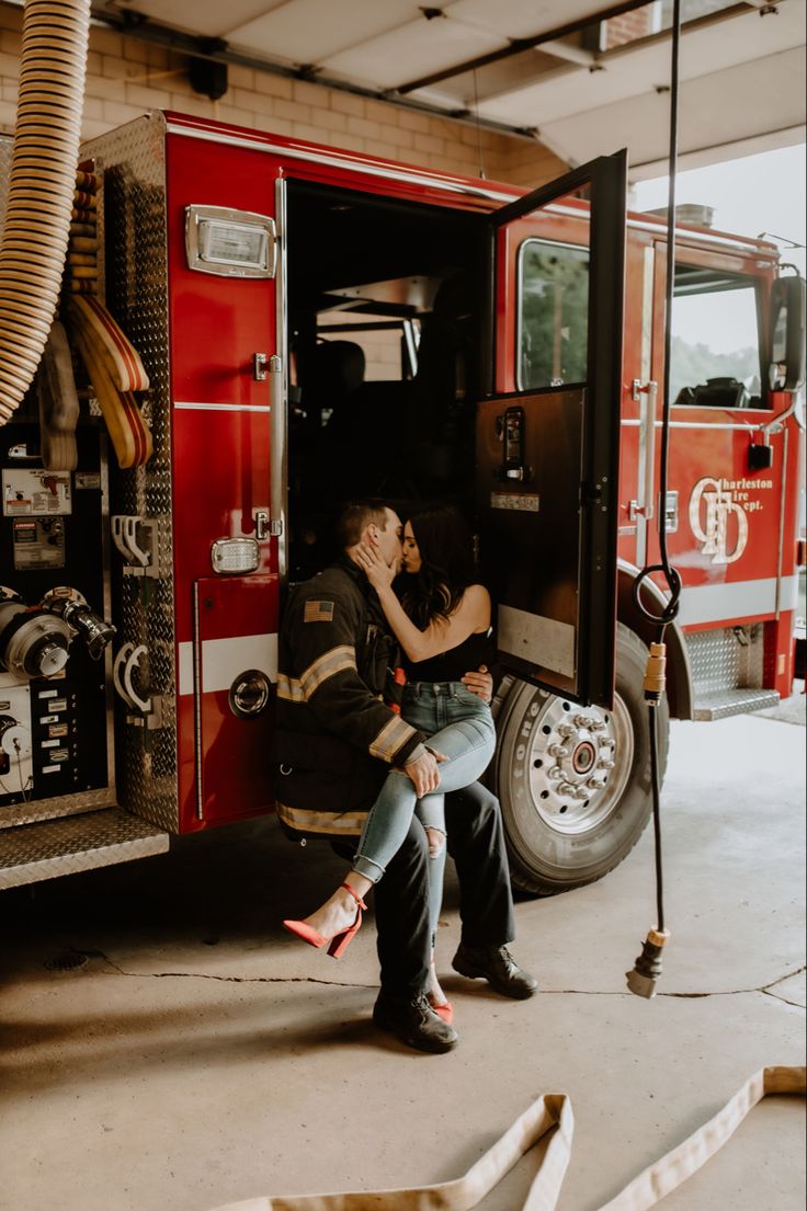 a man and woman are sitting in the doorway of a firetruck, kissing