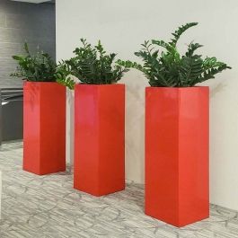 three tall red vases with plants in them