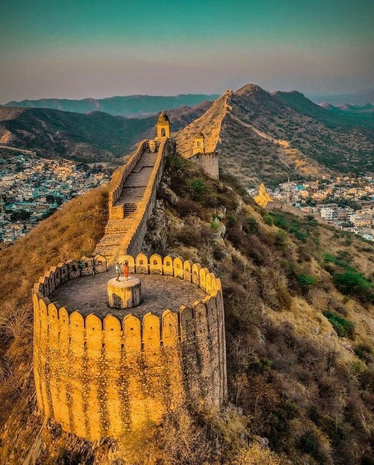 an aerial view of the great wall of china at sunset with mountains in the background